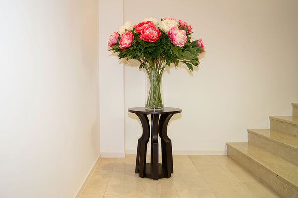 skulpturartiger Beistelltisch mit Blumen vor einer Treppe